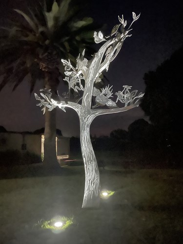 A picture of the new sculpture, Tree of Wonder, at night illuminated by lights installed in the ground.